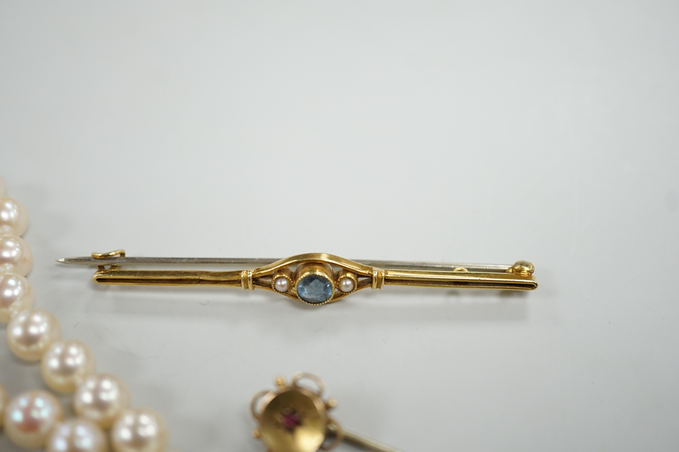 A single strand cultured pearl necklace, with 9ct gold clasp, 46cm, together with a yellow metal and ruby stick pin and a similar gem set bar brooch.